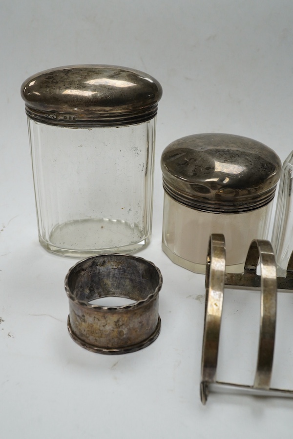 An Art Deco silver five bar toast rack by Charles S. Green & Co Ltd, Birmingham, 1935, 9cm, a silver napkin ring and six assorted silver topped glass toilet bottles. Condition - poor to fair